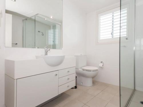 a white bathroom with a sink and a toilet at Pacific Blue Apartment 139, 265 Sandy Point Road in Salamander Bay