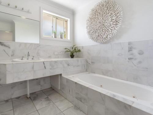 a bathroom with a tub and a sink and a mirror at Pacific Blue Townhouse, 351/265 Sandy Point Road in Salamander Bay