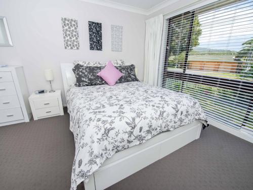 Schlafzimmer mit einem Bett mit einem rosa Kissen und einem Fenster in der Unterkunft Pet Friendly Tomaree Rd 142 Shoal Bay in Shoal Bay