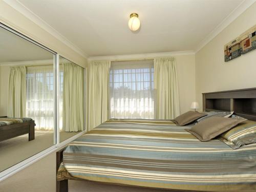 sypialnia z dużym łóżkiem i oknem w obiekcie Reef Close 1 2 w mieście Fingal Bay