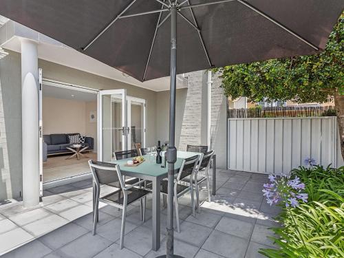 a patio with a table and chairs and an umbrella at Sandcastles 7 8 Ala Moana Way in Fingal Bay