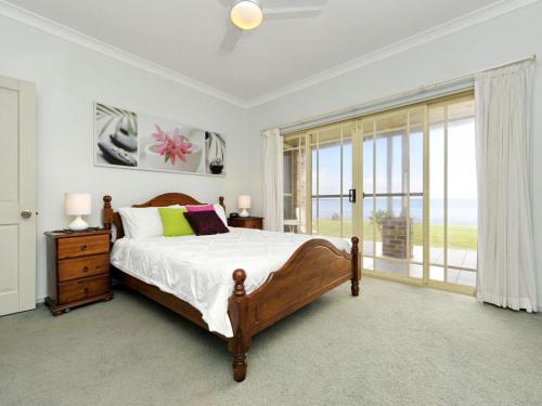 a bedroom with a bed and a large window at Cook Street 4 in Salamander Bay