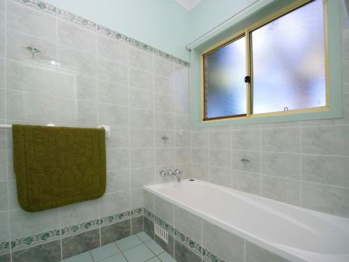 a bathroom with a bath tub and a window at Cook Street 4 in Salamander Bay