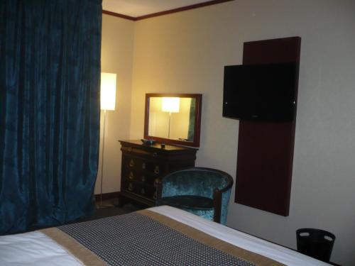 Habitación de hotel con cama, espejo y tocador en Hotel De France, en Montargis