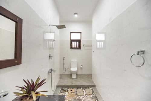 a white bathroom with a toilet and a window at Hotel Calm Haven in Galle