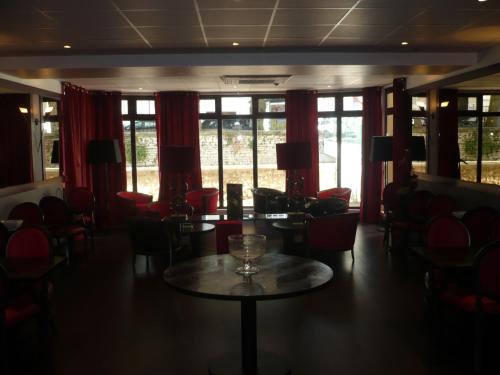 a room with a table and chairs and windows at Hotel De France in Montargis