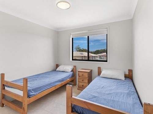 two beds in a room with a window at Fingal Sands 10A Fingal Bay in Fingal Bay
