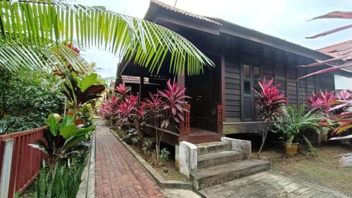 une maison avec une bande de plantes devant elle dans l'établissement Drym Valley Langkawi, à Pantai Cenang