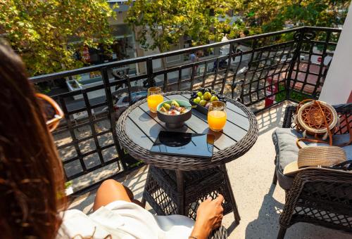 a woman sitting on a balcony with a table with a bowl of fruit at Via Villa Iliotti Rhodos in Rhodes Town