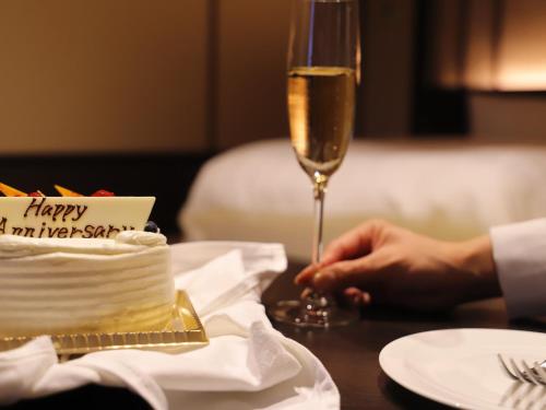 a person holding a glass of champagne next to a birthday cake at Hakone Kowakien Tenyu in Hakone