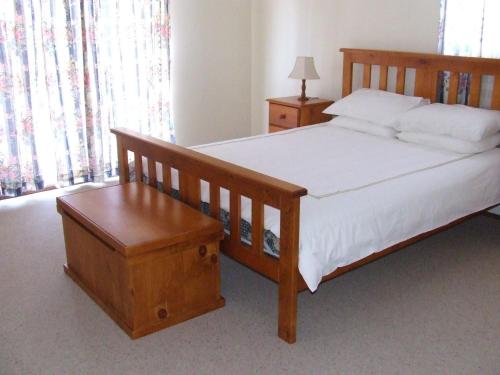 a bedroom with a bed with a wooden frame and a bench at Government Rd 63 Shoal Bay in Shoal Bay