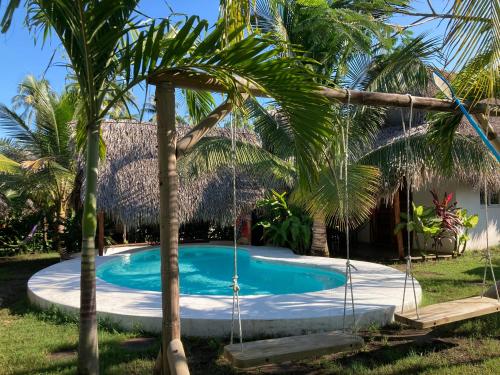 een zwembad in een tuin met palmbomen bij Sunrise El Paredón in El Paredón Buena Vista