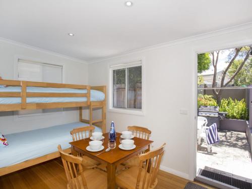 a bedroom with a bunk bed and a table with chairs at Harbour Breeze in Ulladulla