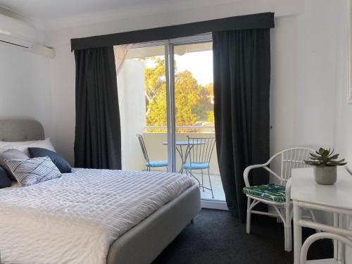 a bedroom with a bed and a balcony with a table and chairs at Seashells Apartment 9, 21-23 Magnus Street in Nelson Bay