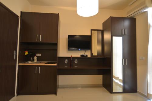 a kitchen with dark brown cabinets and a tv at Solar Apartments in Herceg-Novi