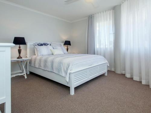 a white bedroom with a white bed and a window at The Anchorage Unit 12 9 Laman Street in Nelson Bay