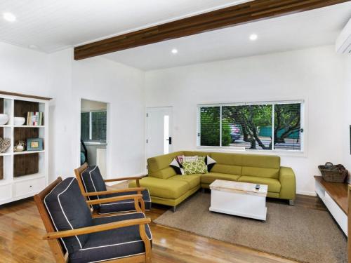a living room with a green couch and chairs at Market Street, 13, The Beach House in Fingal Bay
