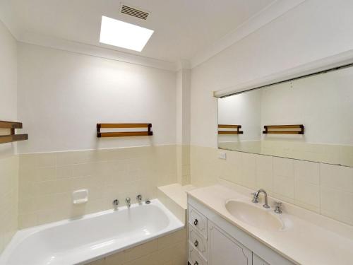 a bathroom with a tub and a sink and a mirror at The Crest Unit 5 6 8 Tomaree Road in Shoal Bay