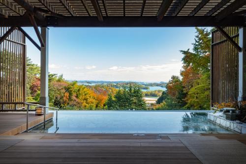 a swimming pool with a view of trees at Hotel Matsushima Taikanso in Matsushima