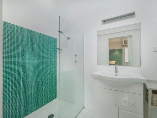 a bathroom with a sink and a glass shower at Tallwoods Beach House in Mollymook