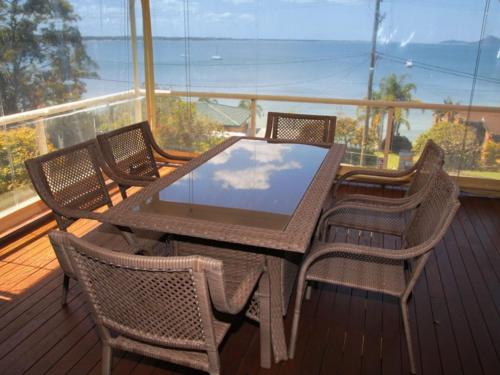a table and chairs on a balcony with a view at Seaside Serenity Soldiers Point in Soldiers Point