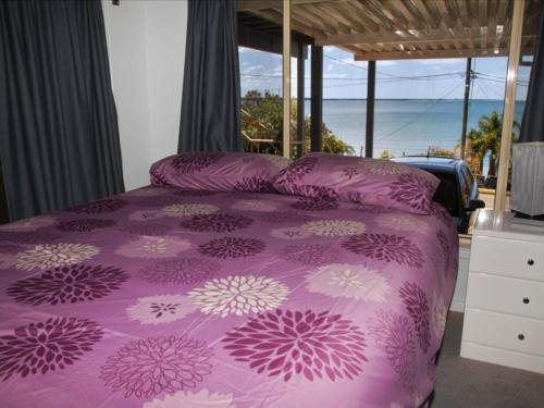 a bedroom with a purple bed with a view of the ocean at Seaside Serenity Soldiers Point in Soldiers Point