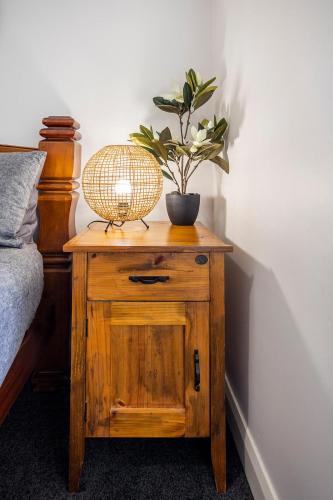 a plant on a wooden table next to a bed at Cabo’s On Currajong Warm, Cosy and Welcoming in Parkes