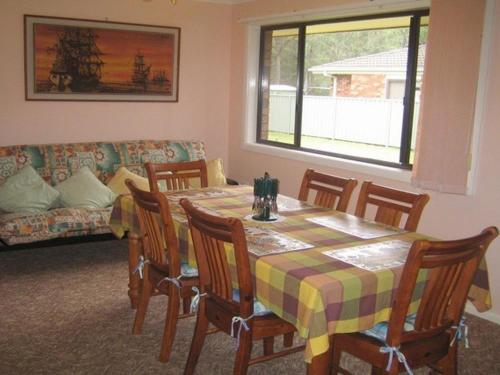 una sala da pranzo con tavolo, sedie e divano di Seascape Macleay Street a Narrawallee