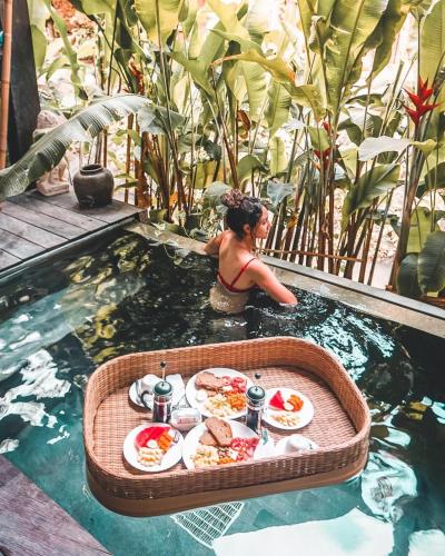 坎古卡拉帕瑜伽精品度假村 的坐在游泳池里带餐盘的女人