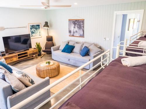 Pandanas Apartments 17A - Mollymook Beach في موليموك: غرفة معيشة مع أريكة وتلفزيون