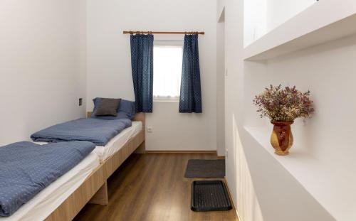 a bedroom with two beds and a vase with flowers at Takács Pince apartman in Hajós