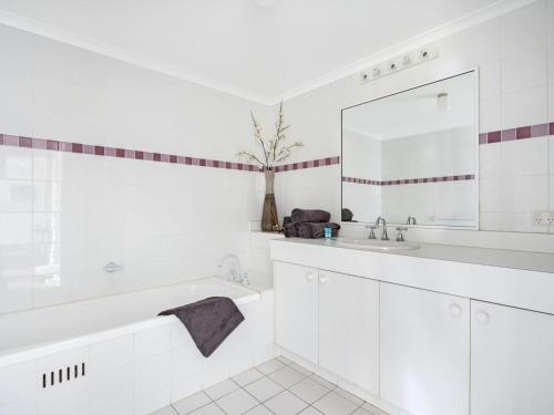 a white bathroom with a tub and a sink at Fathoms 2 in Mollymook