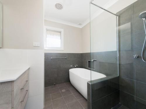 een badkamer met een bad en een glazen douche bij Surfair Unit 1 24 Marine Drive in Fingal Bay