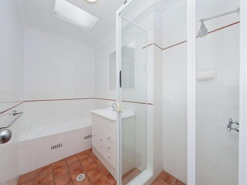 a white bathroom with a shower and a sink at Surf Break Unit 10B Tuna Cresent Upstairs in Fingal Bay