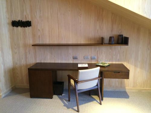 a desk with a chair next to a wooden wall at Valle Corralco Hotel & Spa in Malalcahuello