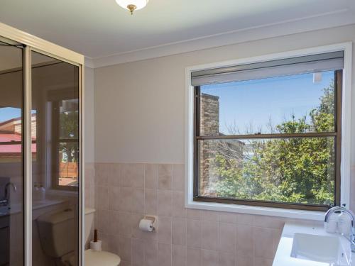 a bathroom with a window and a sink and a toilet at Ocean Views in Mollymook