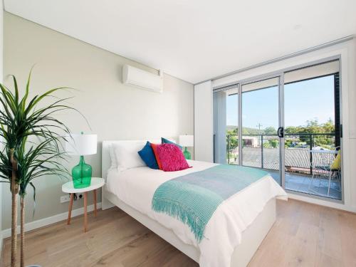 een witte slaapkamer met een bed en een groot raam bij The Shoal Apartments, Unit 201/4-8 Bullecourt Street in Shoal Bay