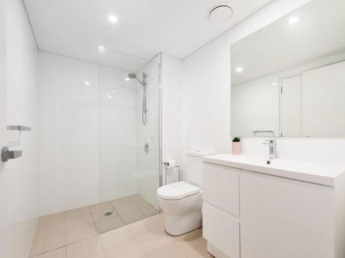 een witte badkamer met een toilet en een douche bij The Shoal Apartments, Unit 201/4-8 Bullecourt Street in Shoal Bay