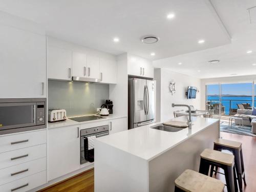 a white kitchen with a sink and a counter top at The Shoal Apartments, Unit 504/4-8 Bullecourt Street in Shoal Bay