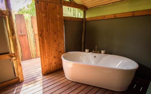 O Bona Moremi Safari Lodge في Khwai: حوض استحمام كبير أبيض في حمام مع أرضيات خشبية
