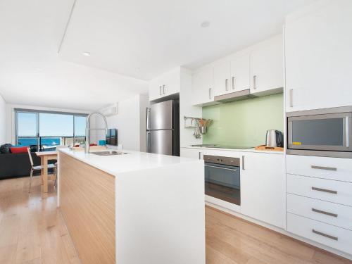 a kitchen with white cabinets and a counter top at The Shoal, Unit 309/4-8 Bullecourt Street in Shoal Bay
