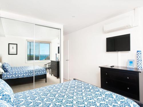 a bedroom with a bed and a tv and a mirror at The Shoal, Unit 309/4-8 Bullecourt Street in Shoal Bay
