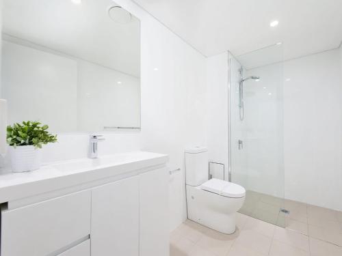 a white bathroom with a toilet and a sink at The Shoal, Unit 309/4-8 Bullecourt Street in Shoal Bay