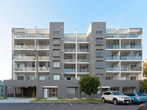 an apartment building with cars parked in a parking lot at The Shoal, Unit 309/4-8 Bullecourt Street in Shoal Bay