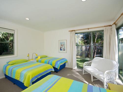 1 dormitorio con 2 camas, silla y ventana en Tuscan Waterfront Unit 1 213 Soldiers Point Road, en Salamander Bay