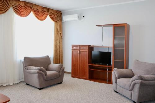 a living room with two chairs and a flat screen tv at Mini-Hotel Morskoi rif in Golubitskaya