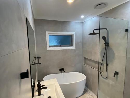 ein Badezimmer mit einer weißen Badewanne und einer Dusche in der Unterkunft Victor Parade 5 in Shoal Bay