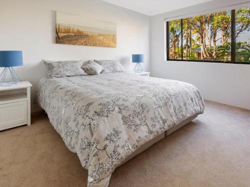 a white bedroom with a bed and a window at Victory Court Unit 1 3 7 Columbia Close in Nelson Bay