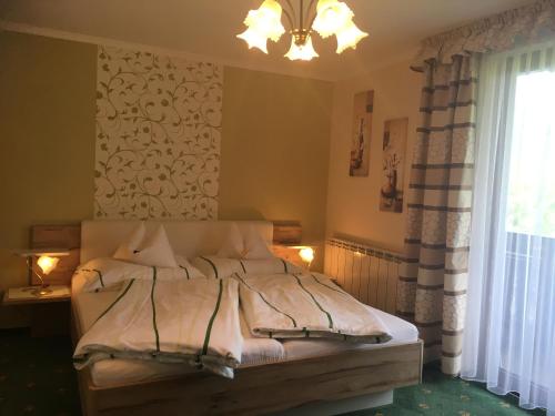 a bedroom with a bed with a chandelier and a window at Gästehaus Kloibergütl in Sankt Gilgen