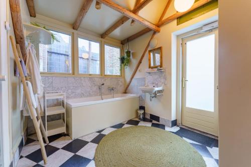a bathroom with a tub and a large window at De Stadsboerderij in Kampen